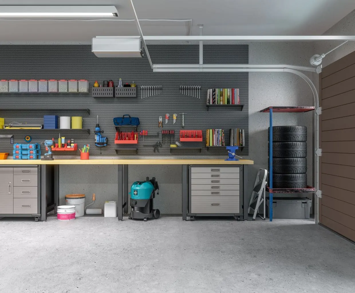Garage workshop with a concrete floor, pegboard tool wall, long workbench, shop vacuum and stacked tires